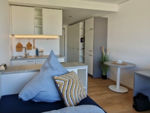 Weiße Küche mit Bett im Vordergrund