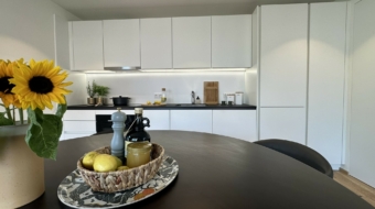 Schwarzer Tisch mit einer weißen Küche im Hintergrund