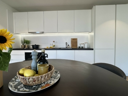 Schwarzer Tisch mit einer weißen Küche im Hintergrund