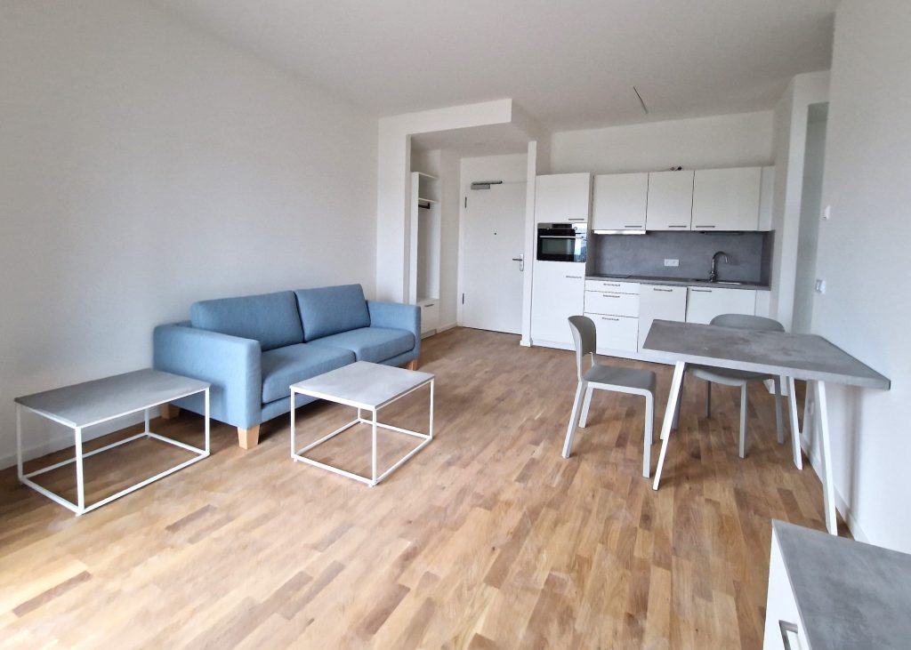 Wohnbereich mit blauem Sofa, Esstisch und weißer Küche – Berlin-Marzahn – Allee der Kosmonauten