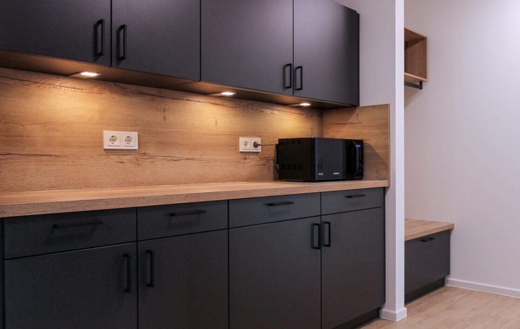 Dark kitchenette with a wooden worktop and microwave – Sengenthal – Employee Apartments