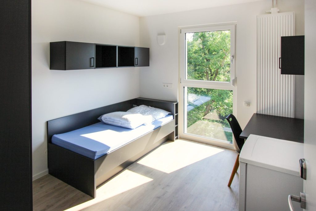 Bedroom with a dark bed and built-in wardrobes – Sengenthal – Employee Apartments